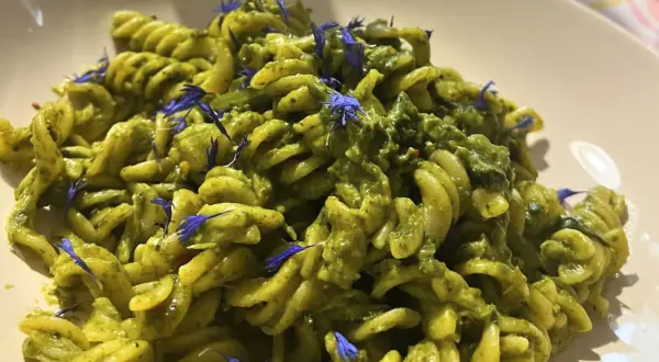 Fusilli-Pasta mit einer cremigen grünen Soße, garniert mit blauen Kornblumen. Ein köstliches italienisches Palmkohl Rezept.