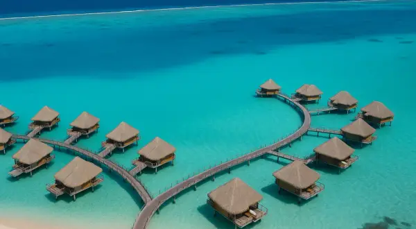 Bora Bora, Polinezja Francuska: domki na wodzie z krytymi strzechą dachami, połączone drewnianymi pomostami, w turkusowej lagunie.