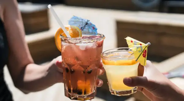 Dwa orzeźwiające drinki, jeden różowy z owocami i pomarańczą, drugi żółty z plasterkiem cytrusa. Idealne na letnie popołudnie, może z dodatkiem białego wina.