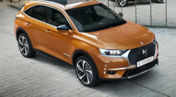 Pomarańczowy Citroën DS7 Crossback lśni na tle lustrzanej ściany. Elegancki SUV prezentuje swoje nowoczesne linie.