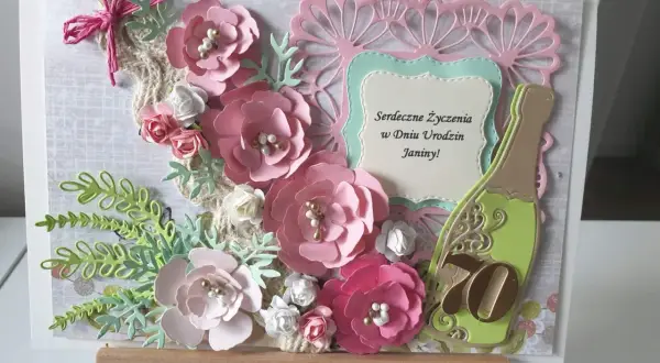 Różana kartka z życzeniami na imieniny Janiny. Butelka szampana i cyfra 70.