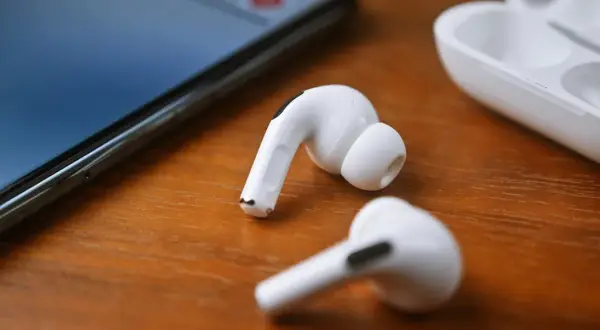 Białe słuchawki JBL leżą obok iPhone'a i etui. Dowiedz się, jak podłączyć słuchawki JBL do iPhone'a, by cieszyć się muzyką.