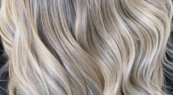 Falujące pasma włosów w odcieniach ciepły blond i jasnego beżu, tworzące subtelne refleksy.