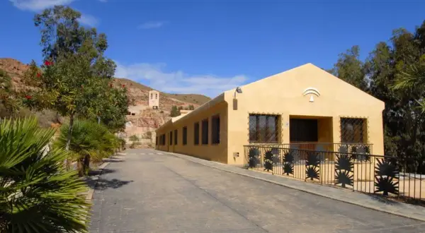 La casa de los volcanes, un edificio amarillo con rejas de palmeras, se alza bajo un cielo azul.