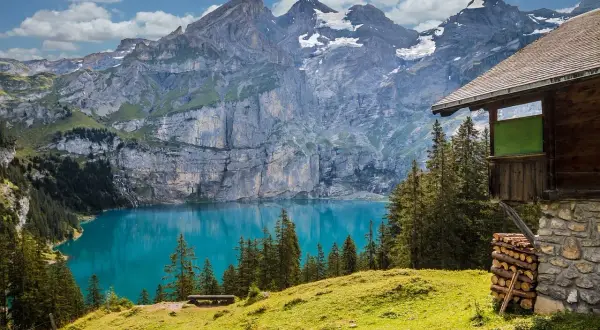 Un rifugio alpino domina un lago turchese, circondato da montagne maestose. Un vero paradiso tra le località di montagna più belle in estate.