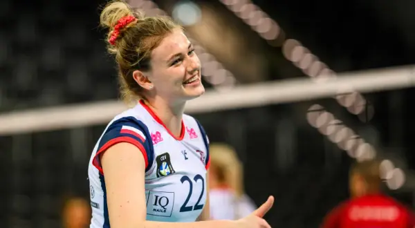 Uśmiechnięta siatkarka Natalia Lijewska w białej koszulce z numerem 22, z czerwoną opaską na włosach, podczas meczu.