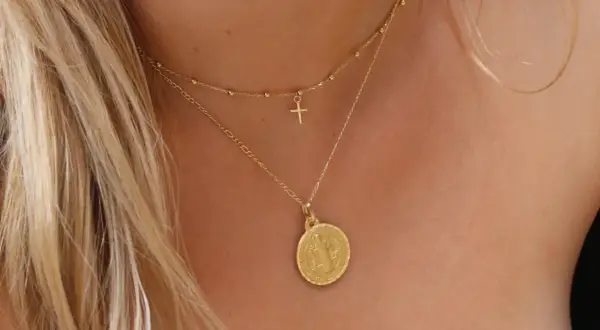Elegante cadena de oro con medalla de San Benito y un pequeño crucifijo.