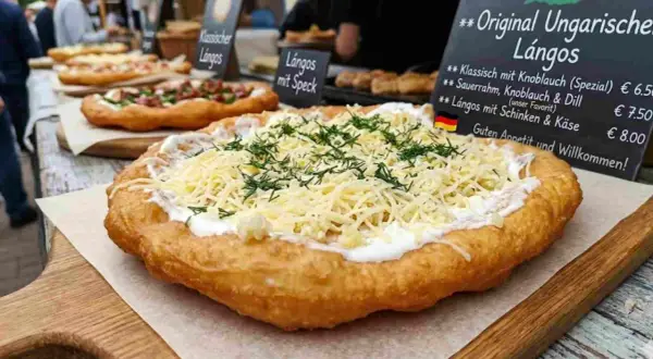 Frisch frittierter Lángos-Teig, belegt mit Sauerrahm, geriebenem Käse und Dill. Daneben weitere Lángos-Varianten.