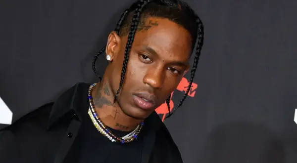 Travis Scott w czarnej koszuli i naszyjnikach, z warkoczami. Fani w Polsce czekają na jego koncert.