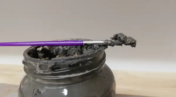 Pinceau violet trempé dans une pâte grise, prête à recoller terre cuite.