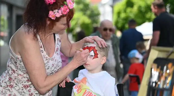 Kind wird beim Stadtfest in Radevormwald von einer Frau mit Spiderman-Maske bemalt.