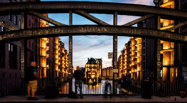 Spektakuläre Fotografie Hamburg: Speicherstadt im Abendlicht, beleuchtete Backsteingebäude spiegeln sich im Wasser.