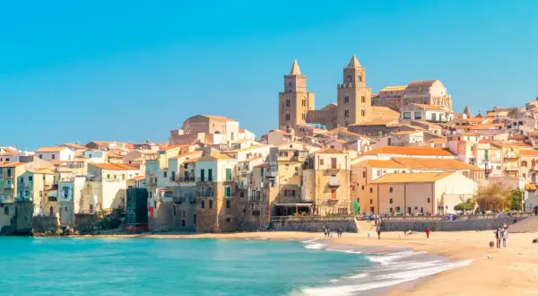 La costa di Cefalù con le sue case colorate e il mare azzurro. La cattedrale domina il panorama.