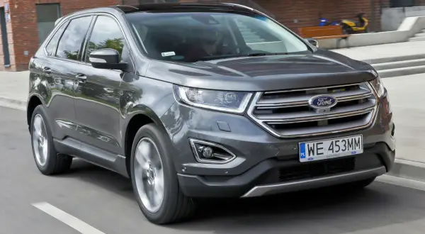 Szary Ford Edge w ruchu miejskim. Kierowca zadowolony, co potwierdzają pozytywne ford edge opinie.
