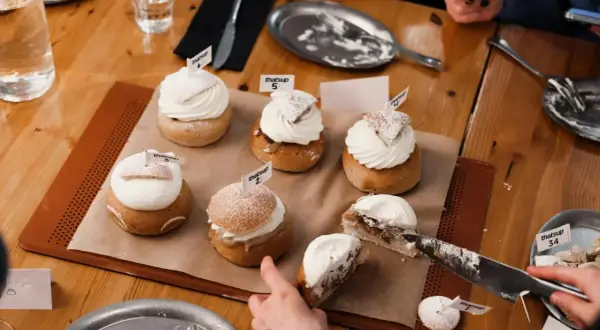 En härlig samling semlor med fluffig grädde och flaggor. En semla är uppskuren, redo för en smak av ritorno semla.