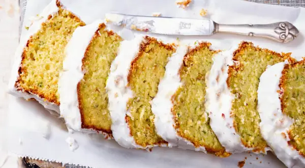 Saftiger Zucchini Kuchen mit weißer Glasur, in Scheiben geschnitten, bereit zum Genießen.