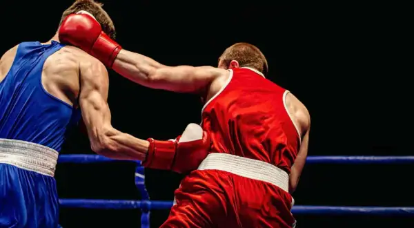 Boxers in a ring. The boxer in red throws a punch, showing how to know if your southpaw or orthodox by their stance.