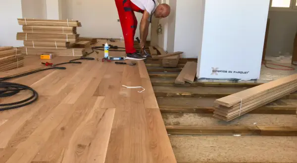 Instalador coloca elondo madera en un suelo.