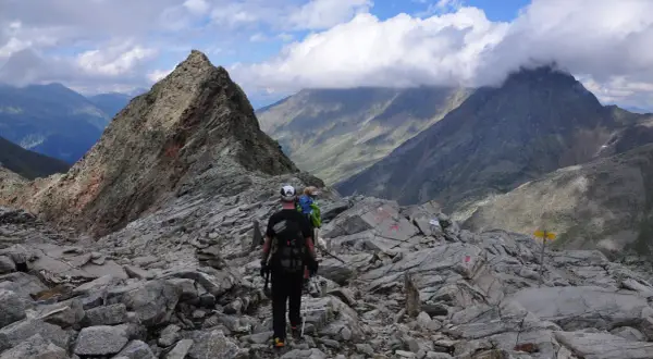 Wanderer auf einem steinigen Grat, mit Blick auf den wilden Freiger und dramatische Wolken.