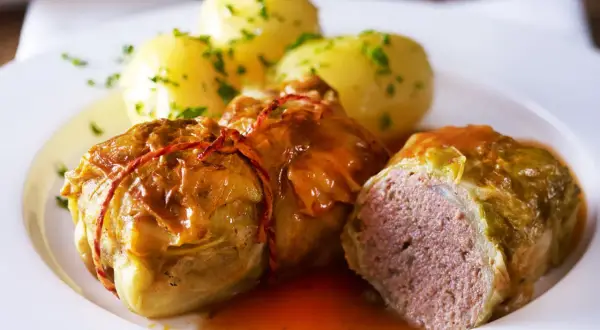 Herzhafte Kohlrouladen mit Kartoffeln, ein Klassiker der deutschen Gerichte, serviert auf einem weißen Teller.