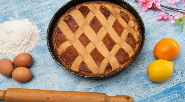 Pastiera appena sfornata con un reticolo di pasta frolla. Quante strisce sulla pastiera? Otto, per un dolce perfetto.