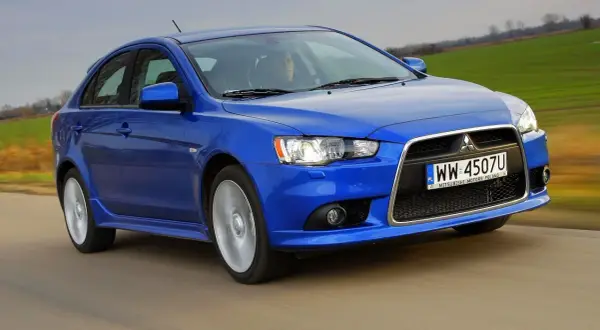 Niebieski Mitsubishi Lancer 9 w ruchu, z widocznym kierowcą i polskimi tablicami rejestracyjnymi.