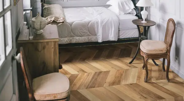 Sypialnia z łóżkiem i meblami, podłoga w jodełkę z kolekcji Marazzi Treverksoul Neutral.