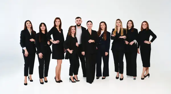 Grupa profesjonalistów w czarnych garniturach na białym tle.