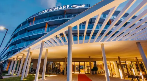 Nowoczesny hotel Infa Mare z charakterystycznym zadaszeniem i czerwonym dywanem zaprasza do swojego wnętrza.