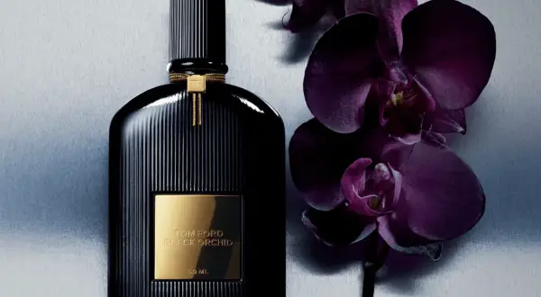 Elegancka butelka perfum Tom Ford Black Orchid 100ml obok ciemnofioletowych storczyków.
