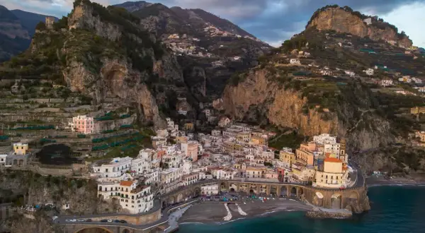 Un borgo pittoresco sulla Costiera Amalfitana, tra i paesi più belli d'Italia, aggrappato alla roccia con case colorate e mare blu.