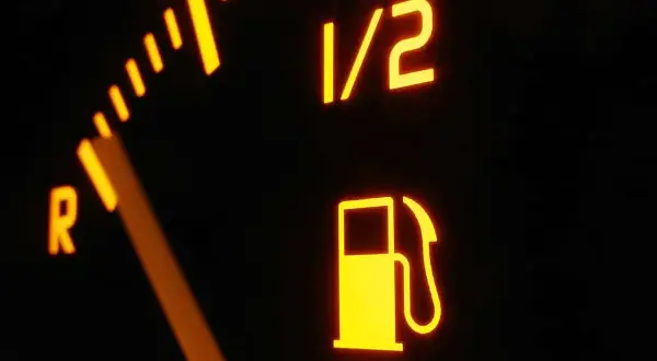 Wskaźnik paliwa pokazuje, że zbliża się jazda na rezerwie. Strzałka jest blisko litery R, a ikona dystrybutora świeci się na żółto.