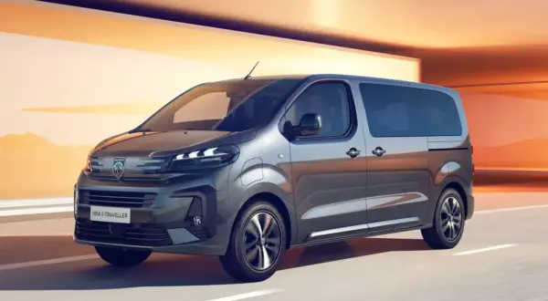 Nowy Peugeot e-Traveller, czyli ile waży bus 9-osobowy, pędzi po drodze na tle pomarańczowych ścian.