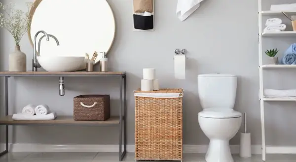 Bagno moderno con lavabo, specchio, cesto in vimini e rotolo di carta igienica. L'altezza porta rotolo carta igienica è ben visibile.