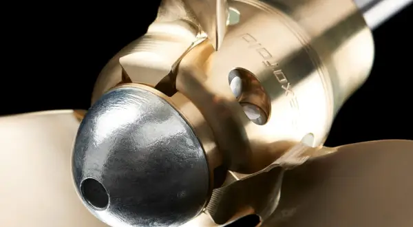 Dettaglio di un'elica a passo fisso in bronzo lucido, con un mozzo argentato e pale che si estendono verso l'esterno.