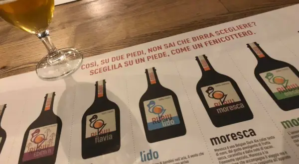 Un bicchiere di birra e un menu del birrificio Rubiu con diverse etichette di birra.