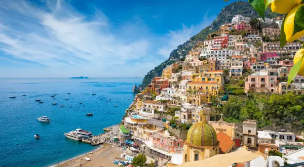 Positano, un gioiello da scoprire tra le cose da visitare in Campania. Case colorate a picco sul mare blu, barche e una spiaggia vivace.