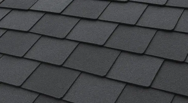 Close-up of dark grey, textured recycled shingles on a roof, showcasing their layered pattern and durable appearance.