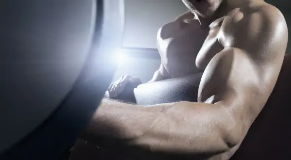 Muskulöser Mann trainiert im Fitnessstudio, seine Arme sind definiert und ohne Fettansatz.