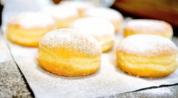 Frisch gebackene Krapfen, mit Puderzucker bestäubt, warten auf das Krapfen Rezept.