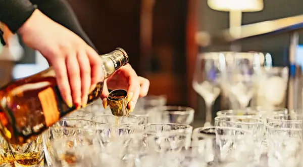 Händer häller upp whisky i små glas. En härlig whiskyprovning i Edinburgh väntar.