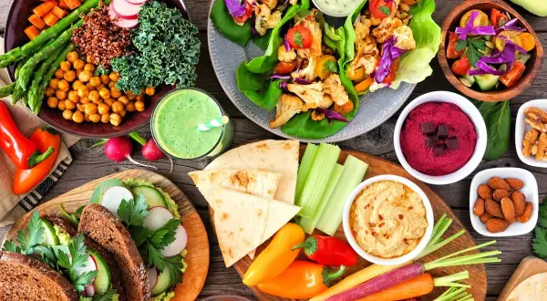 Kolorowe warzywa, hummus, smoothie i pieczywo – to wszystko pokazuje, co to jest weganizm: pyszne i zdrowe jedzenie bez produktów odzwierzęcych.