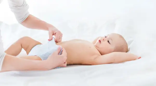 Mama zmienia pieluszkę, a maluch ma czarną kupę.