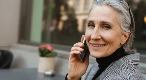 Uśmiechnięta Grażyna rozmawia przez telefon, ciesząc się swoim imieninowym dniem.