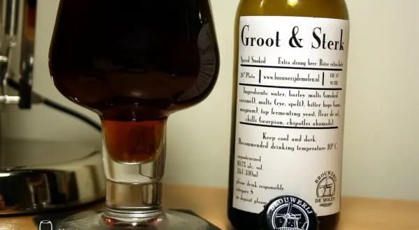 Groot & Sterk, piwo z browaru De Molen, to nie jest zwykłe piwo, to prawdziwy rarytas. Ciemny trunek w kieliszku, obok butelka z etykietą.