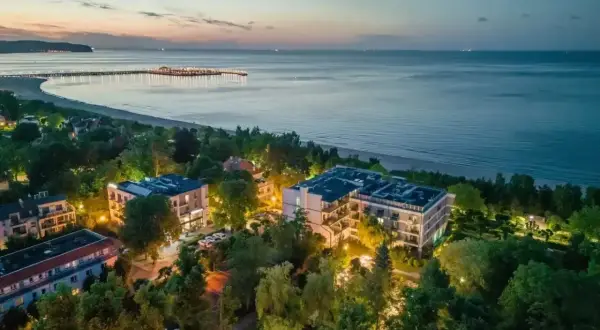 Widok z lotu ptaka na nadmorskie apartamenty i molo o zmierzchu.