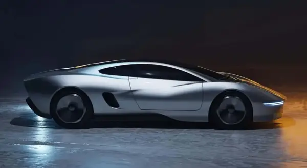 Elegancki, srebrny, nowy jaguar o futurystycznym designie, z wąskimi światłami LED i aerodynamiczną sylwetką, stoi na mokrej nawierzchni.