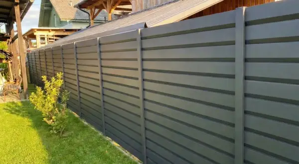 Moderna recinzione esterna grigia a listelli orizzontali, un'ottima idea per delimitare il giardino con stile e privacy.