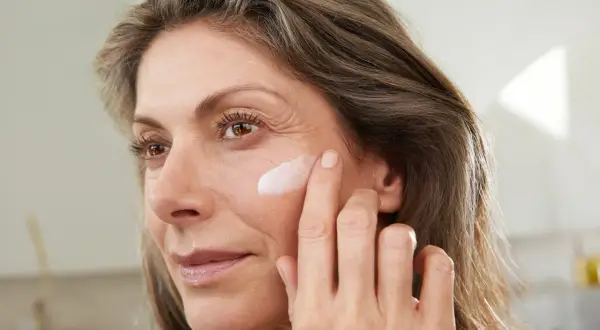Frau trägt abends keine Creme ins Gesicht, sondern nur einen Tupfer auf die Wange.