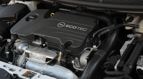 Silnik Opel Astra 1.4 Turbo Ecotec. Widoczny turbosprężarka, kolektor dolotowy i osłona silnika.